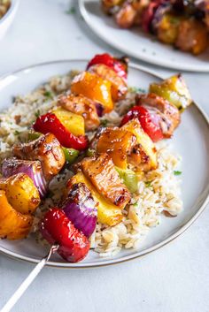 chicken and vegetable kabobs served over rice on a plate