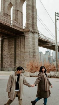 two people holding hands in front of the brooklyn bridge