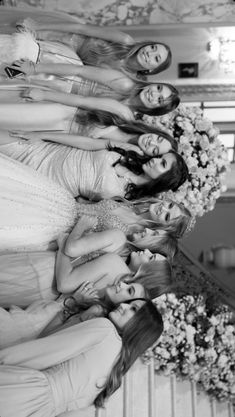 a group of young women standing next to each other in front of a flower arrangement