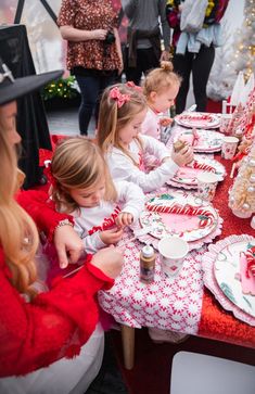 a group of children sitting at a table with plates and cups in front of them