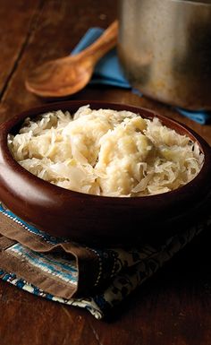 a wooden bowl filled with mashed potatoes on top of a blue and brown napkin