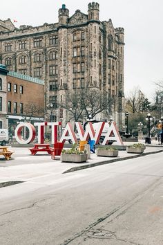 a large sign that says ottawa on the side of a road in front of some buildings