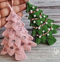 two handmade christmas trees are being held by someone's hands on a wooden table