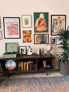 a living room filled with lots of art on the wall above a bookshelf