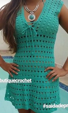 a woman standing in front of a pool wearing a green crochet dress and necklace