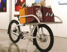 a bike with two bags on the back and one bag on the front, parked in an art gallery