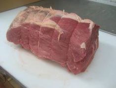 a piece of raw meat sitting on top of a cutting board next to a knife