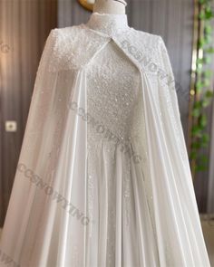 a white wedding gown with a cape on top