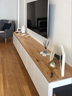 a living room with wooden flooring and white furniture on top of the tv stand