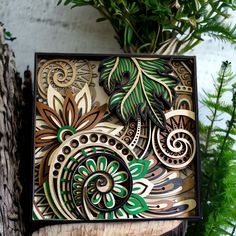 an intricately designed wooden box sitting on top of a tree stump next to a potted plant