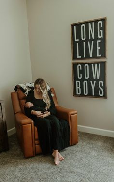 a woman sitting in a chair with her baby on her lap and two signs above her