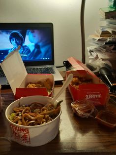 an open laptop computer sitting on top of a desk next to a bowl of food