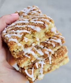 a hand holding a piece of cake with white icing