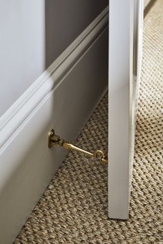 an open door with a gold handle on the floor next to a carpeted floor