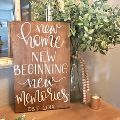 a wooden sign sitting on top of a table next to a vase filled with flowers