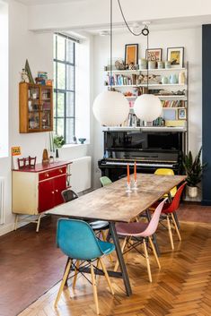 a dining room table with chairs and a piano in the background