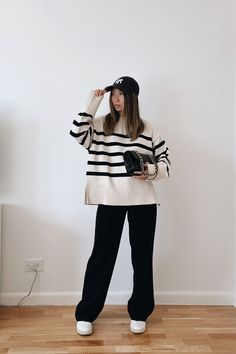 New york city based fashion influencer Lauren Lora wearing a casual cold weather outfit. She’s wearing a black and white oversized striped sweater, black wide leg trousers, white sneakers, a yankees hat and a black chanel classic flap. How To Style A Vest, Striped Sweater Outfit, Oversized Striped Sweater, Cold Weather Outfit, Classic Style Outfits, Pull Oversize, Black Wide Leg Trousers, Stripe Outfits