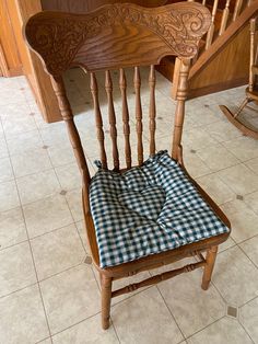 a wooden chair with a blue and white checkered seat pad on the bottom of it