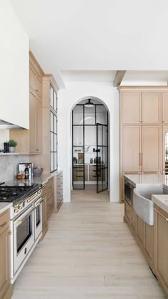 a kitchen with wooden cabinets and marble counter tops, along with an arched doorway leading to the dining room