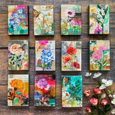 six square paintings with flowers on them sitting on top of a wooden table next to a vase