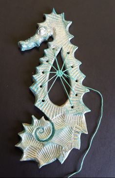 a close up of a sea horse made out of paper mache and yarn on a black surface