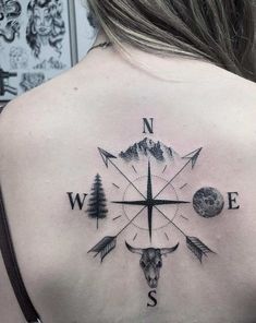 a woman's back with a compass tattoo on her shoulder and an animal head