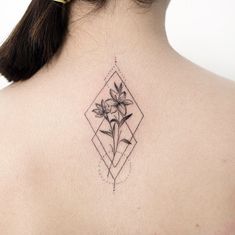 the back of a woman's neck with a flower tattoo on her left shoulder