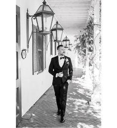 a man in a tuxedo is walking down the sidewalk