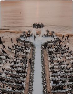 an aerial view of a wedding ceremony on the beach with people standing in front of it