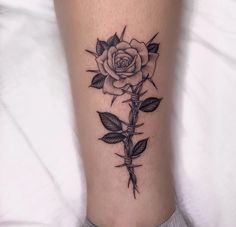 a black and white rose tattoo on the leg