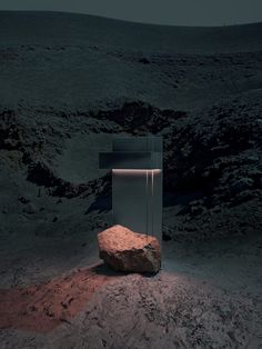 a rock sitting on top of a dirt covered ground next to a glass box with a light in it