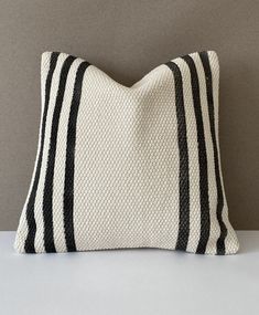 a black and white striped pillow sitting on top of a gray table next to a wall