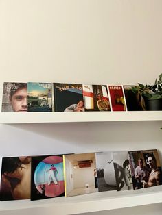 the shelf is holding several books on it and there are plants in front of them