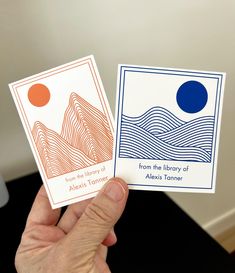 two cards in the palm of a person's hand, one with an orange and blue circle on it