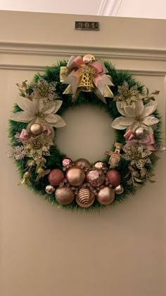 a christmas wreath with ornaments hanging on the wall next to a white door and window