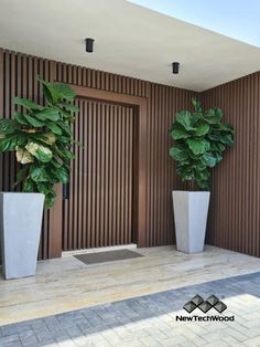 two tall planters sitting next to each other on the side of a building with wooden slats