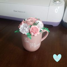 a pink coffee cup with flowers in it on a table next to a printer machine