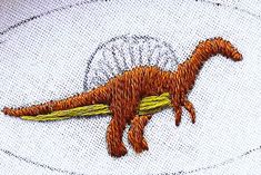 an embroidered t - shirt with a dinosaur on it