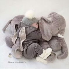 a baby sleeping on top of an elephant stuffed animal