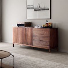 a living room with a large painting on the wall next to a wooden cabinet and coffee table