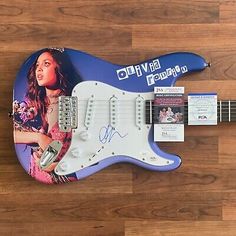 an electric guitar with a signed photo on the body and strings, sitting on a wooden floor