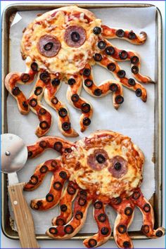 an octopus pizza with olives and pepperoni is on a baking sheet, ready to be cooked