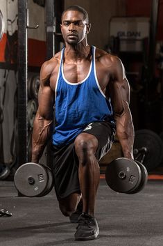 a man is squatting with two dumbbells in front of him and looking at the camera