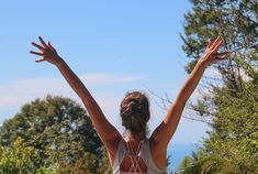 a woman reaching up to catch a frisbee in the air with her hands