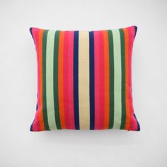 a multicolored striped pillow sitting on top of a white wall