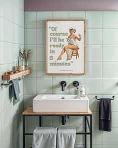 a bathroom with a sink, towel rack and framed poster on the wall above it