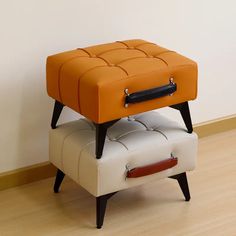 an orange and white ottoman sitting on top of a wooden floor next to a wall