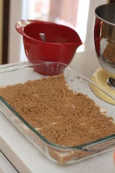 a glass dish filled with brown sugar next to a measuring cup and oranges on a counter