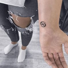 a person with a small tattoo on their wrist holding onto the hand of another person