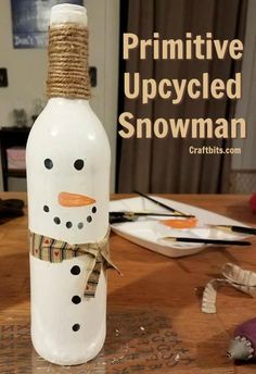 a bottle with a snowman painted on it sitting on top of a wooden table